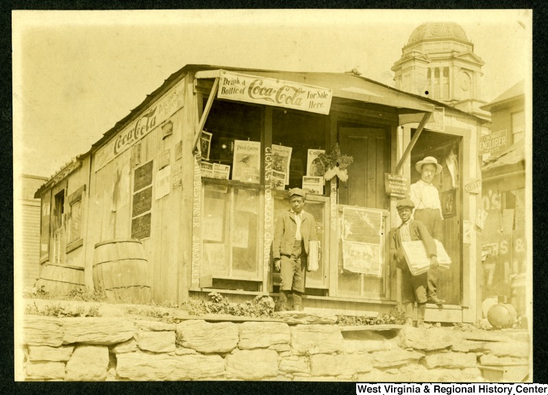 Two African-American Newsboys and Unidentified man stand outside C. N Chilins Newsstand