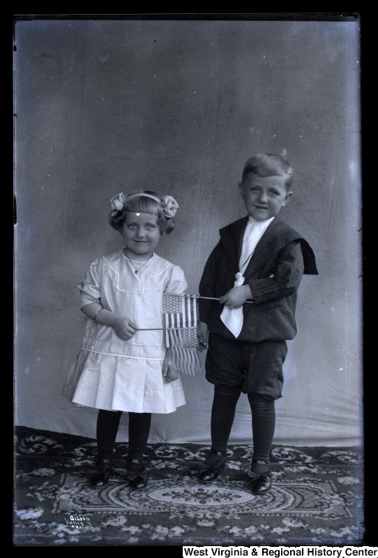 Portrait of two young children waving small flags