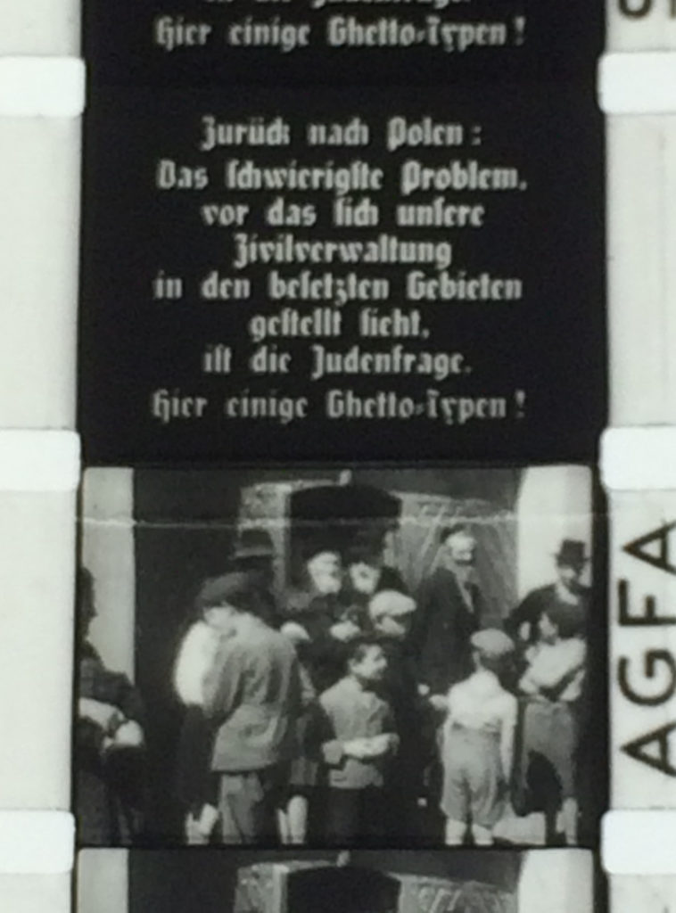 Film strip showing a frame of text in German above an image of presumably Polish Jews