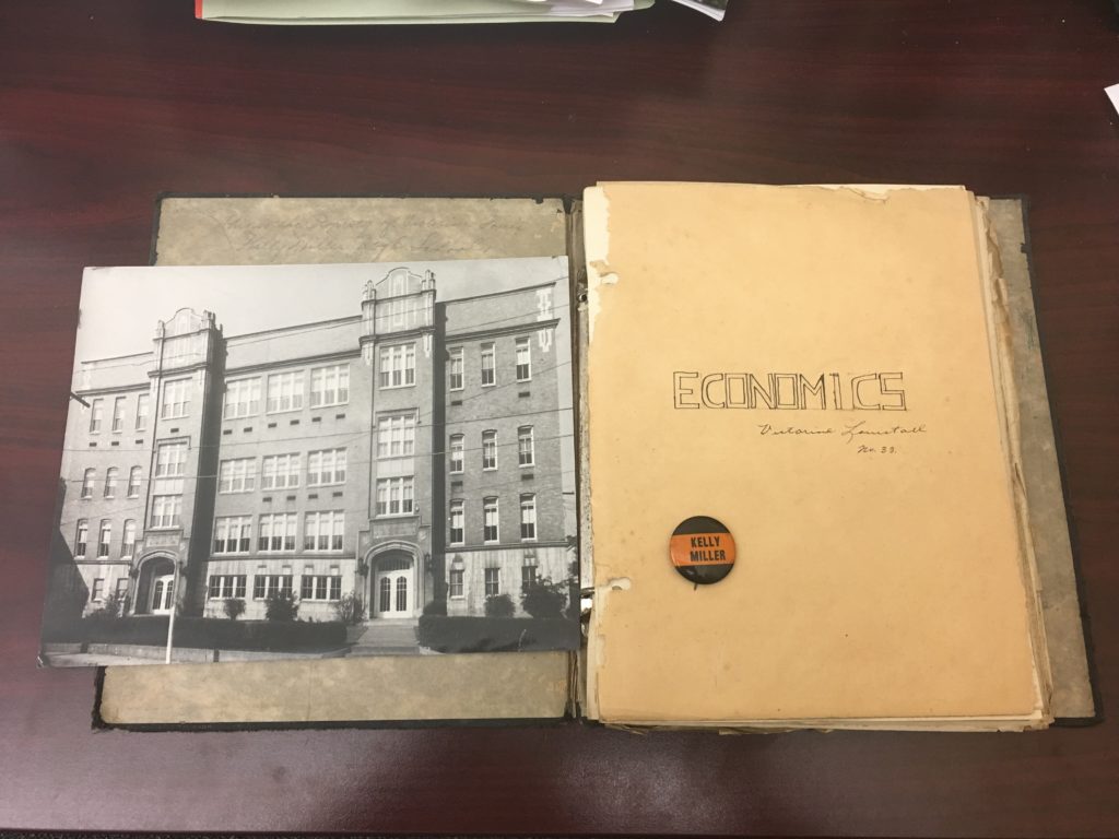 Photograph of Kelly Miller High School, economics notebook, and Kelly Miller pin