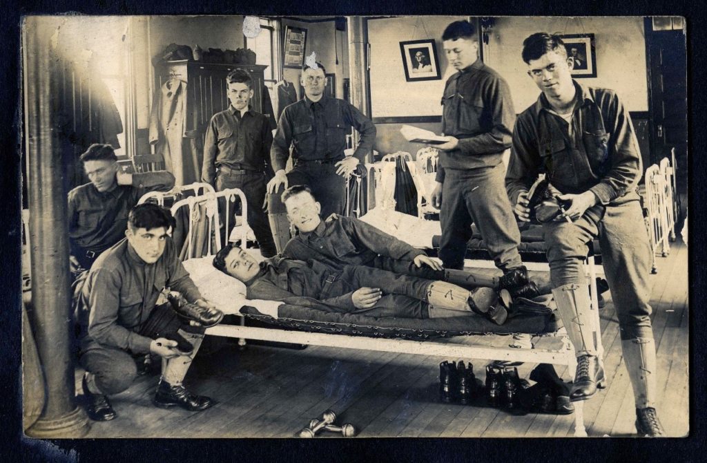 Group of soldiers posed on and around a bed in a barracks