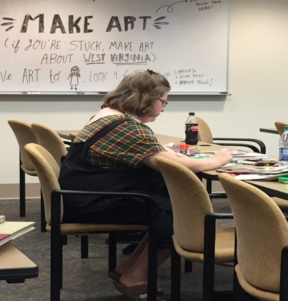 Woman sitting at table working on a zine