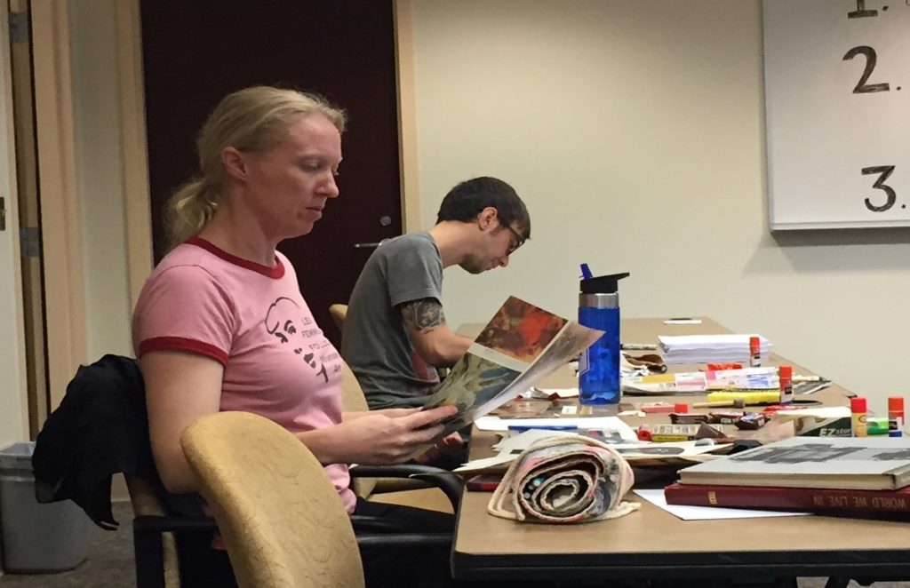 Woman and man sitting at table working on zines