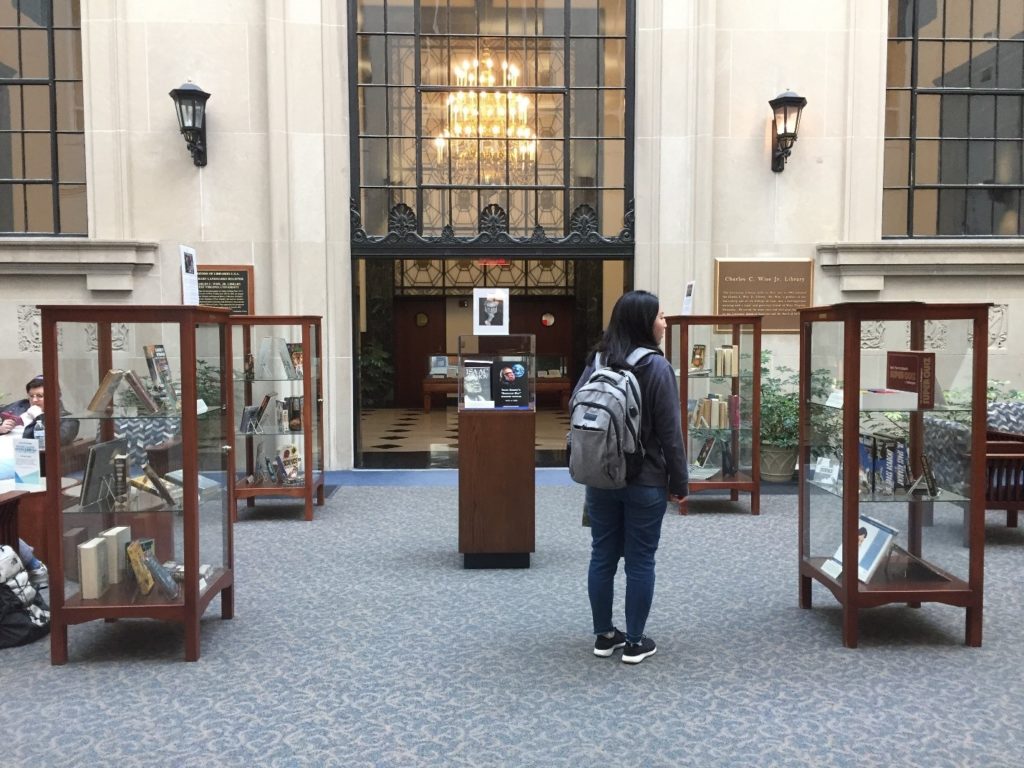 Student viewing Isaac Asimov materials in glass cases in the library atrium