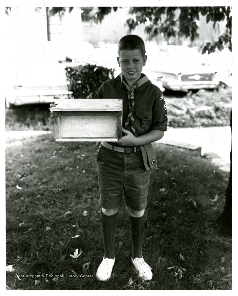 Boy scout holding bird feeder