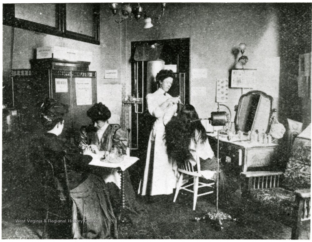 Woman dressing the hair of another woman, while another woman does the nails of a fourth woman.