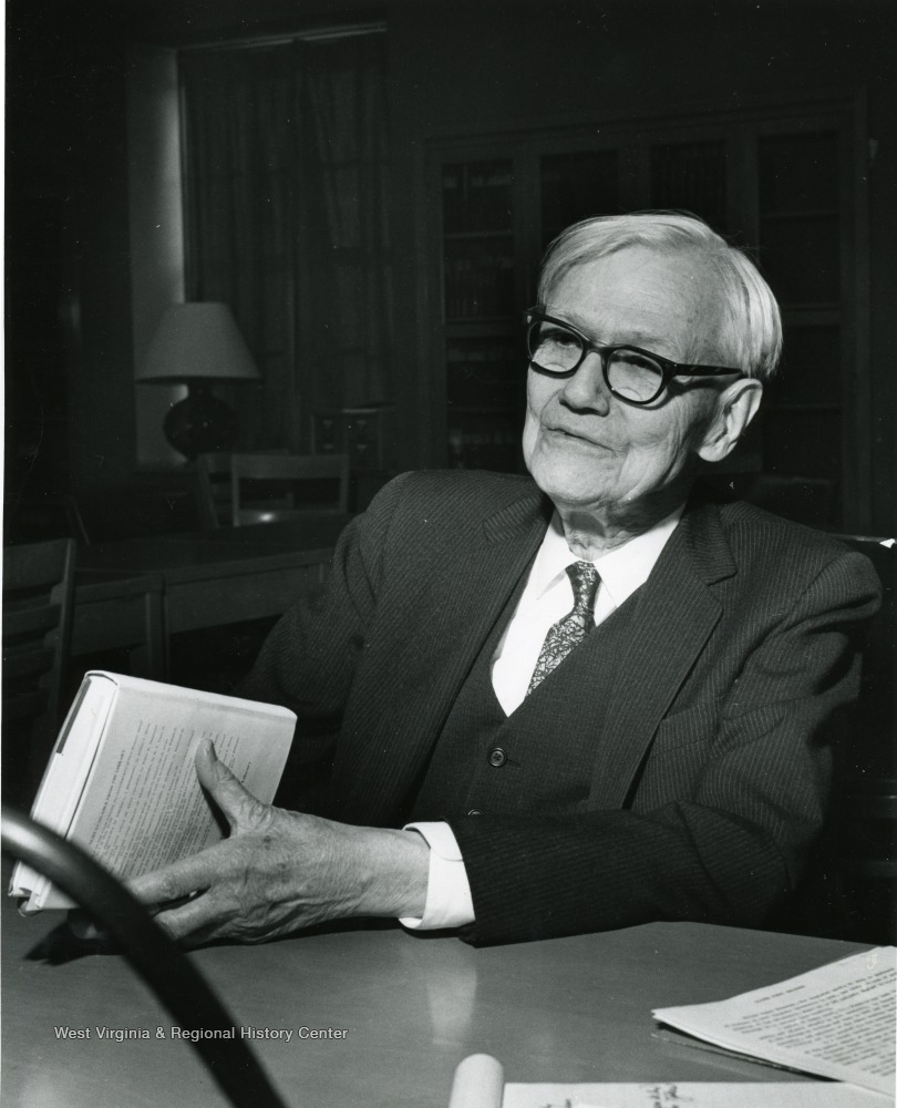 Oliver Chitwood as an older man, seated, holding a book