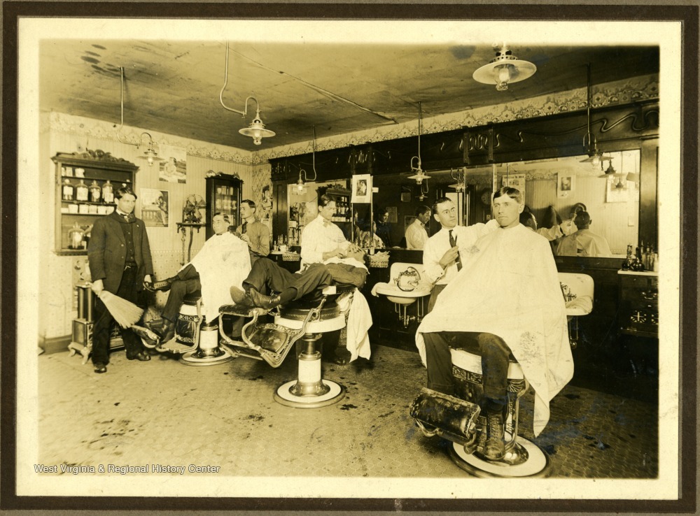 Interior of a barbershop full of barbers and customers