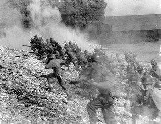 Photo of soldiers holding guns, running up a beach amid smoke