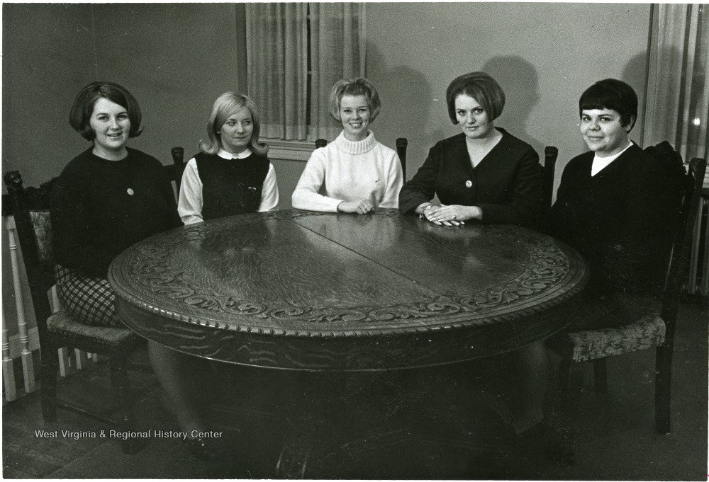 Portrait of five college aged women seated at a circular table