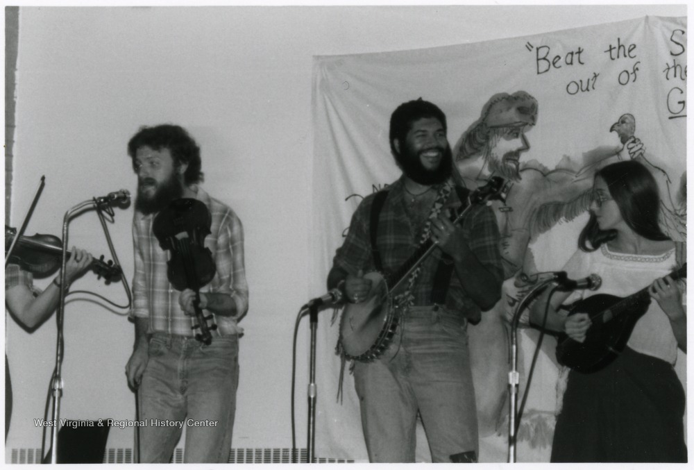 Fiddlers, banjo player, and mandolin player standing with microphones