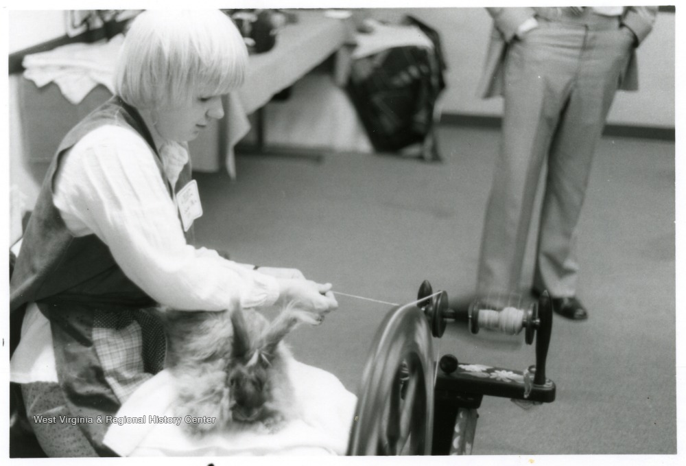 Person spinning yarn at a spinning wheel