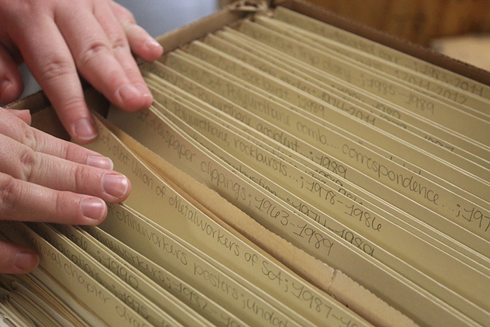 Hands flipping through labeled folders in a box.