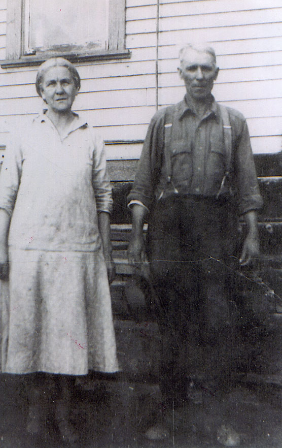 Woman and man standing in 1930s era casual clothing next to a house.