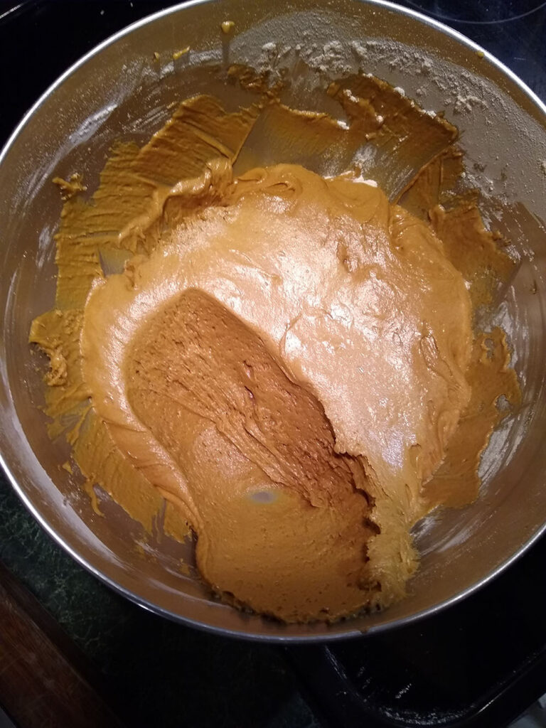 Bowl of brown cake batter with a scoop taken out.