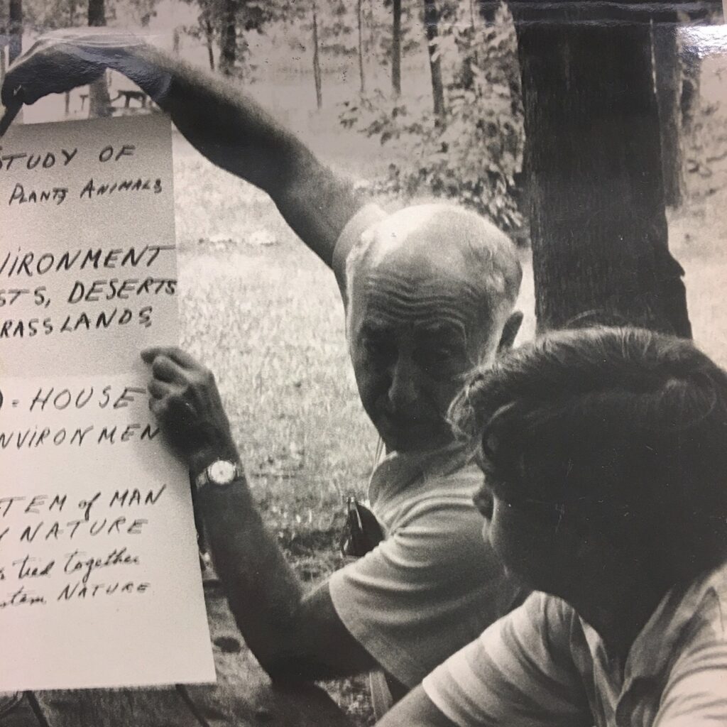 Older man holding up a poster, talking to younger man beside him