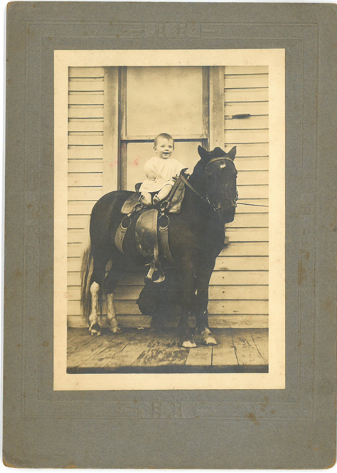 Smiling baby seated on a pony