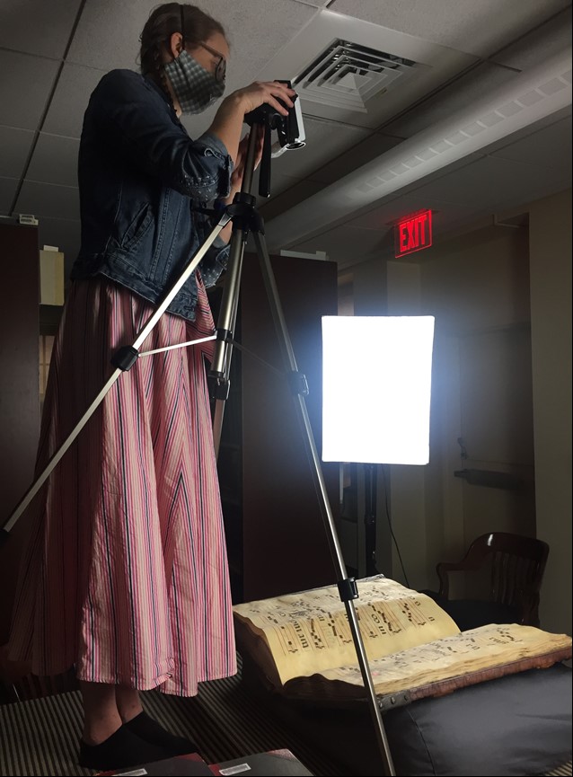 Woman operating camera on tripod to photograph a book