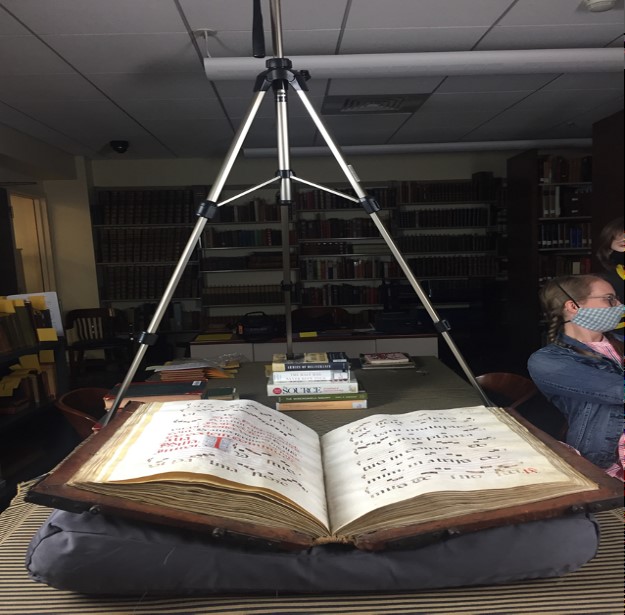 Open book resting on a pillow beneath a tripod