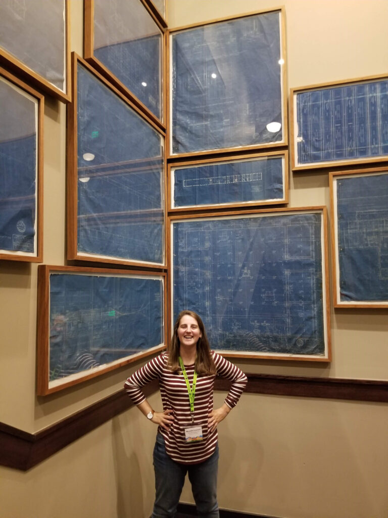 Woman standing in front of framed blueprints