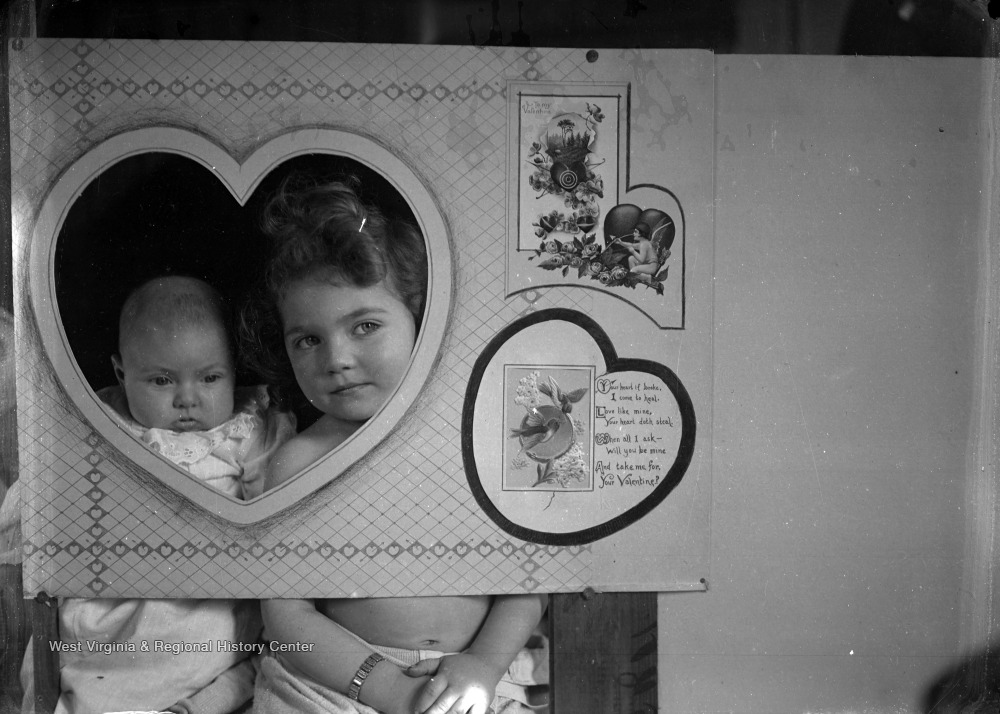 Two children in a cutout of a larg Valentine's Day card