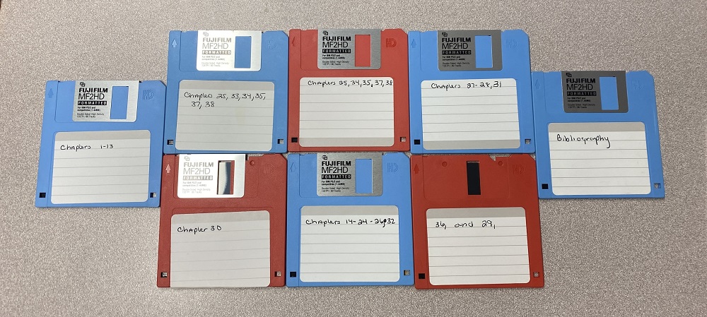 8 Floppy disks, 5 blue and 3 red, lined up on a table.
