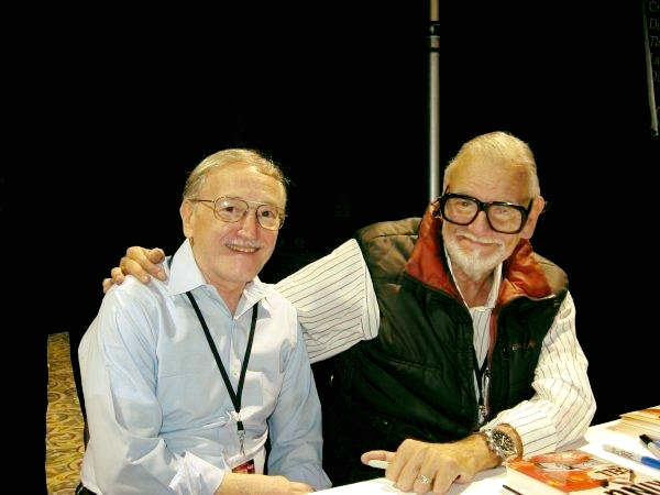 A picture of John Russo, left, and George Romero, right. Romero has an arm around Russo's shoulder. Both are older men with glasses.